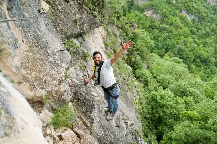 Climber on the via ferrata route above the forest