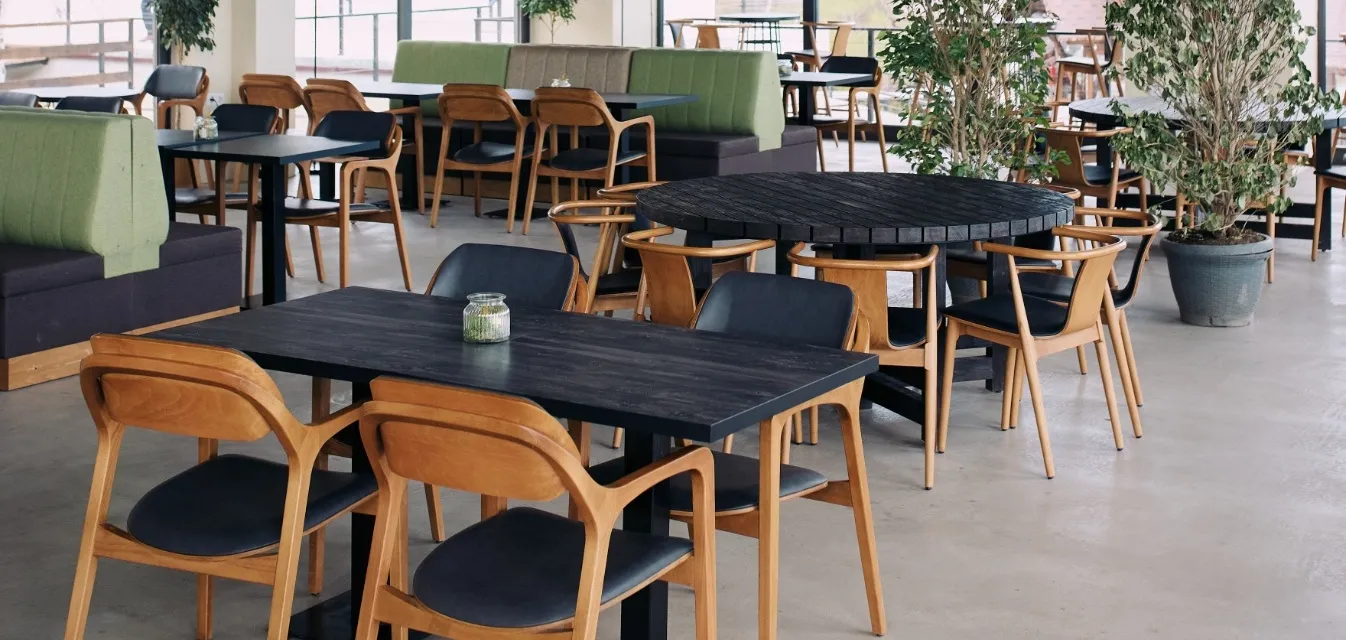 Dining hall of the Apaga restaurant with wooden chairs and green banquettes